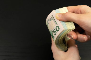 Kadınların elleri, arka planda fotokopi alanı olan yüz dolarlık banknotların arasında hareket eder.