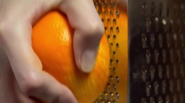 Aşçı portakal tadını rendeleyiciye elle sürer.