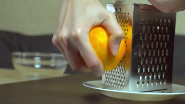 Cocinar frota la ralladura de naranja a mano sobre un rallador — Vídeos de Stock