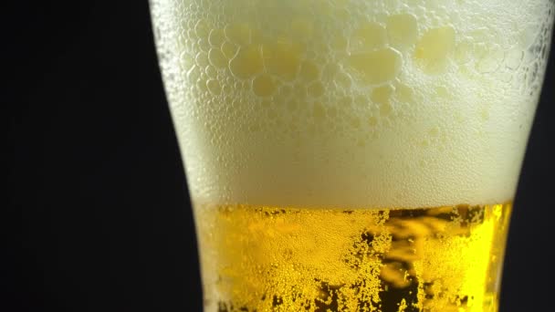 Close-up van bierbelletjes met schuim in een glas. Licht bier. — Stockvideo