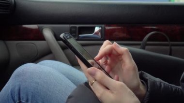 Kadın eli, akıllı telefon arabada otururken sosyal ağlara takılıyor.