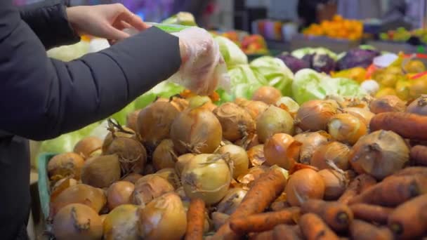 Eine Frau pflückt Zwiebeln aus einem Korbregal in einem Supermarkt — Stockvideo