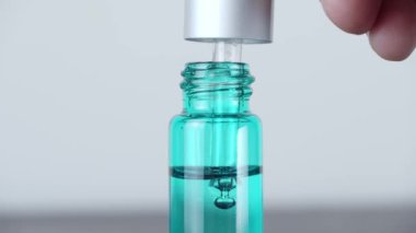 Önemli bir damla yağ pipetten kozmetik şişesine düşer, makro..