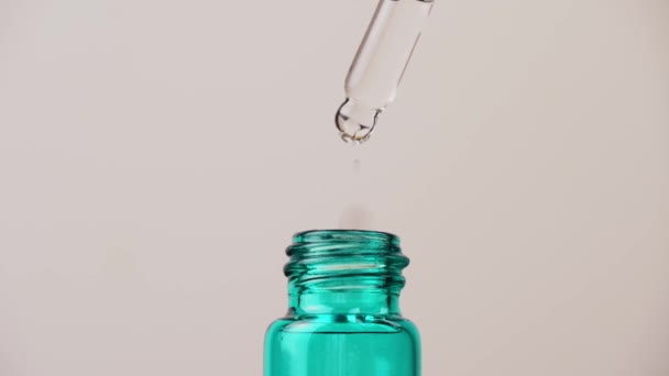Uma gota de óleo essencial cai da pipeta para a garrafa cosmética, macro. — Vídeo de Stock