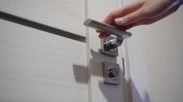 La mano de una mujer con una manicura abre una puerta de madera a una habitación blanca. Para cerrar. — Vídeo de stock