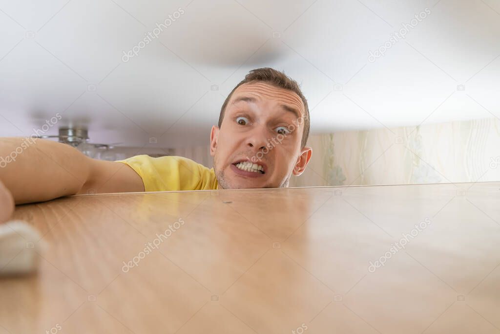 Concept of cleaning the house. a man wipes dust from a tall cabinet in his house. he goes up to the ceiling and runs a rag over the dusty cabinet.
