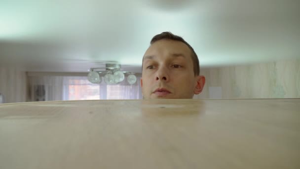 Koncepcja sprzątania domu. mężczyzna wyciera kurz z wysokiej szafki w swoim domu — Wideo stockowe
