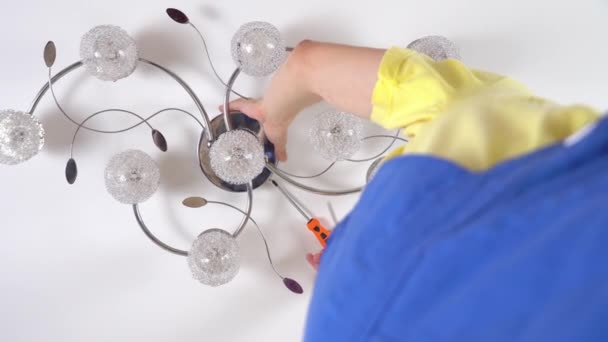 Unge man elektriker, reparerar en ljuskrona, — Stockvideo