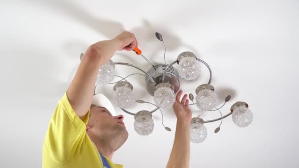Un joven electricista, repara una araña, atornilla el tornillo — Vídeos de Stock