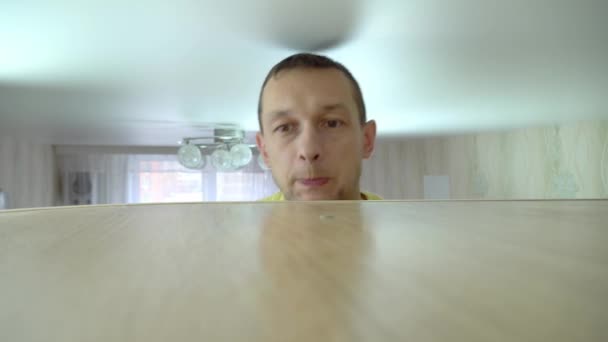 Концепция уборки дома. мужчина стирает пыль с высокого шкафа в своем доме — стоковое видео