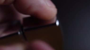 Bir adamın eli bir benzin çakmağı açar ve bir zippo yakar.