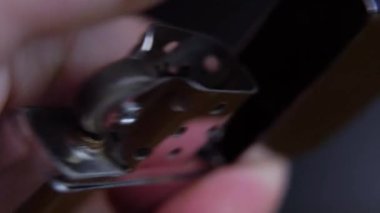 Bir adamın eli bir benzin çakmağı açar ve bir zippo yakar.