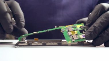 Usta bir servis merkezinde akıllı telefonu tamir eder, kapatır.