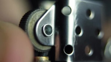 Bir adamın eli bir benzin çakmağı açar ve bir zippo yakar.