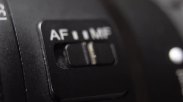 Dedo que cambia el interruptor de enfoque automático en una lente de cámara — Vídeos de Stock