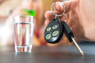 Adamın eli arabanın anahtarlarını bir yığın votka ve bir kızın arka planında tutuyor. Sarhoş araba kullanma kavramı