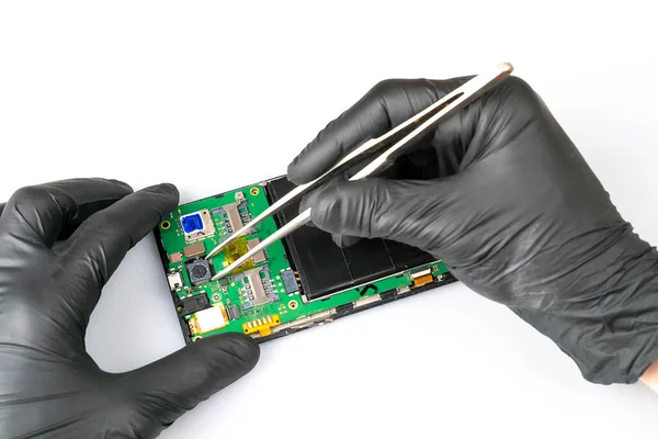 Fix the phone.A technician or master repairs a mobile phone, he installs and changes the camera in the motherboard. Hands, gloves, macro