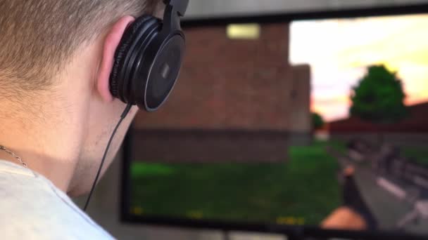 Ein Spieler mit Kopfhörern im Raum spielt ein Videospiel. — Stockvideo