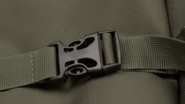 Erkek eli kopar ve sırt çantasının yeşil kumaşındaki Fastex 'in düğmelerini aç.