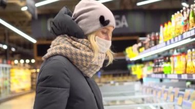 Tıbbi maske takan bir kadın süpermarketten alışveriş yapıyor.