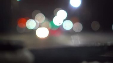 Gece şehirde araba trafiği, arabanın içindeki kamera. Koyu bulanık arkaplanda bokeh