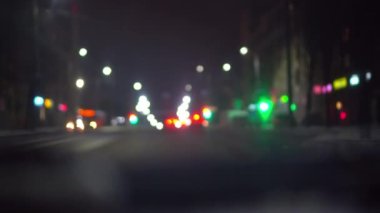 Gece şehirde araba trafiği, arabanın içindeki kamera. Koyu bulanık arkaplanda bokeh