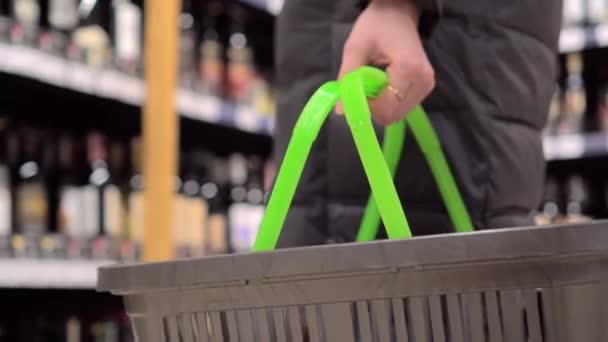 A woman holds a basket in a supermarket close-up. — Stock Video