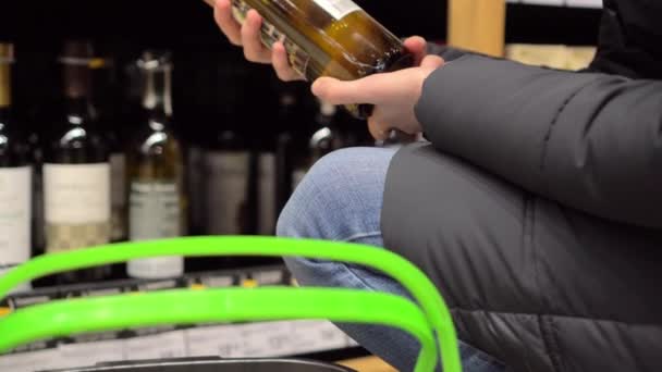 Una mujer elige vino en un supermercado, la venta de alcohol — Vídeo de stock