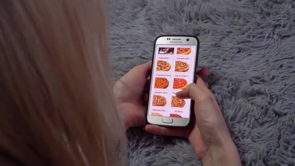 Una mujer pide comida en casa desde una tienda en línea, un teléfono inteligente — Vídeo de stock