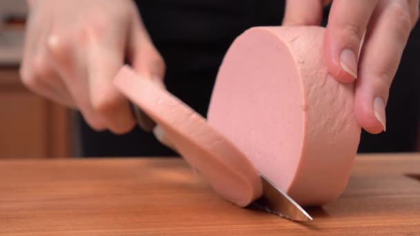 A nők kezei főtt kolbászt szeletelnek egy vágódeszkán.. — Stock videók