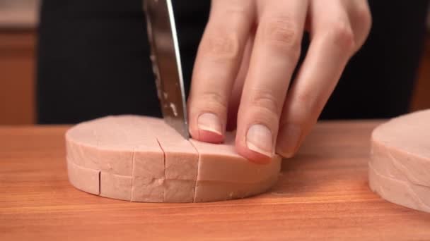 A nők kezei főtt kolbászt szeletelnek egy vágódeszkán.. — Stock videók