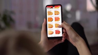 Kızın biri ekranda fast food pizza dağıtım sitesi olan bir telefon kullanıyor..