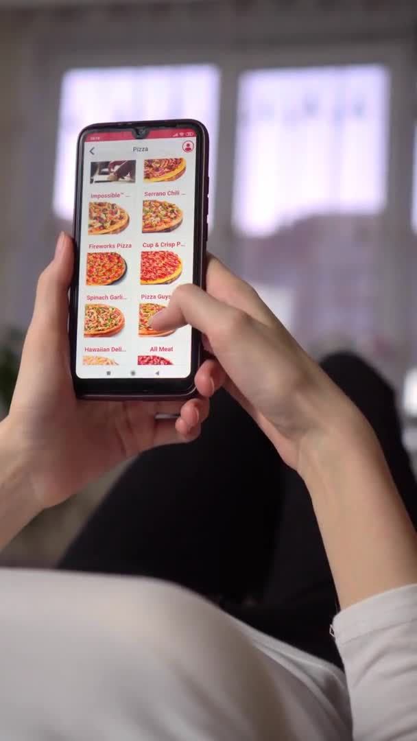 Μια γυναίκα παραγγέλνει φαγητό στο σπίτι από ένα ηλεκτρονικό κατάστημα, ένα smartphone — Αρχείο Βίντεο
