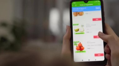 Kadının eli listeyi karıştırır ve taze sebze ve meyve siparişi verir..