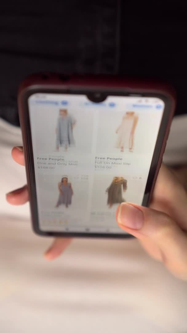 Eine Frau betrachtet ein Produkt in einem Online-Bekleidungsgeschäft und entscheidet, was sie kaufen will. — Stockvideo