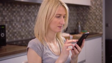 Güzel bir kız evde oturuyor ve akıllı telefon uygulaması kullanıyor..