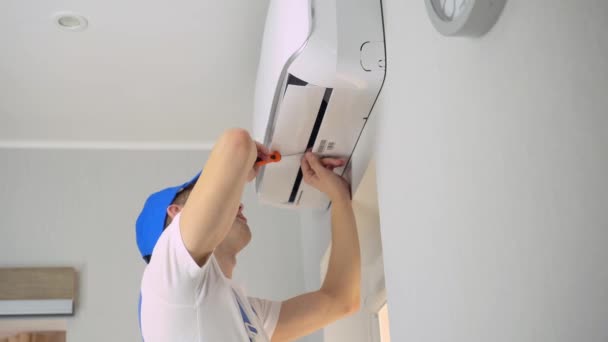 Un jeune maître en uniforme répare le climatiseur de l'appartement. — Video