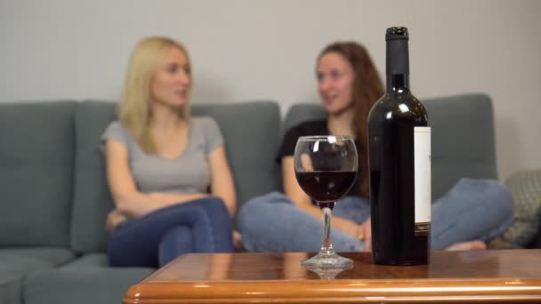 Två tjejer chattar hemma och dricker rött vin. — Stockvideo