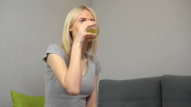 Junge schöne Blondine trinkt Limonade oder Saft zu Hause. — Stockvideo