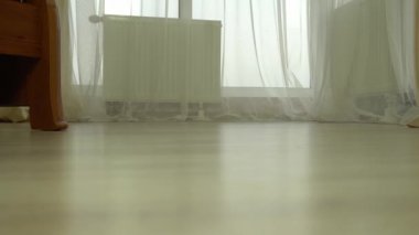 Genç bir kadın evdeki sıcak ahşap zeminde yalın ayak yürüyor.