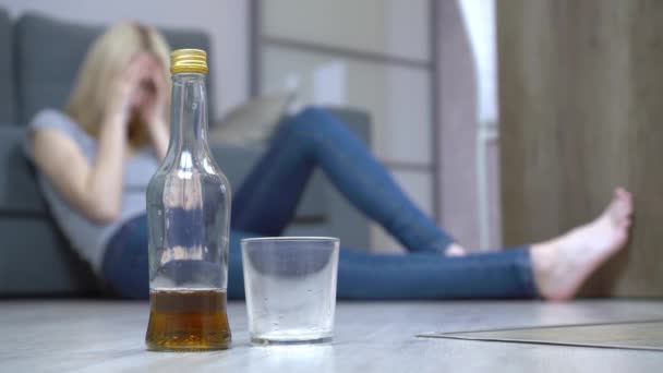 Una joven duerme después de beber en casa en el suelo. Alcoholismo femenino — Vídeos de Stock