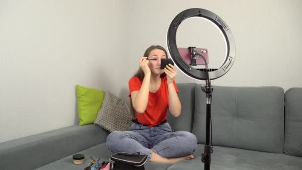 Skönhet bloggare registrerar makeup tutorial hemma medan du sitter på soffan på kameran. — Stockvideo