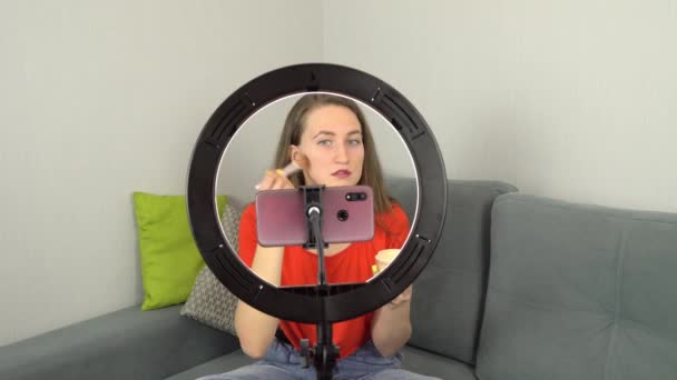 Блогер красоты записывает уроки макияжа дома, сидя на диване на камеру. — стоковое видео