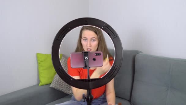 Blogueiro de beleza grava tutorial de maquiagem em casa enquanto está sentado no sofá na câmera. — Vídeo de Stock