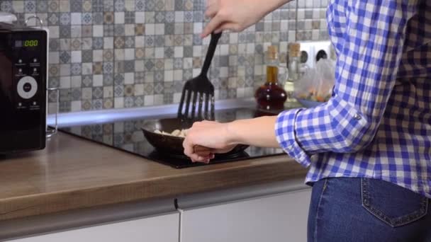 家庭のモダンなキッチンでフライパンで夕食を作る女性. — ストック動画