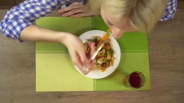 Una mujer come verduras fritas con trozos de carne. Primer plano desde arriba. — Vídeos de Stock