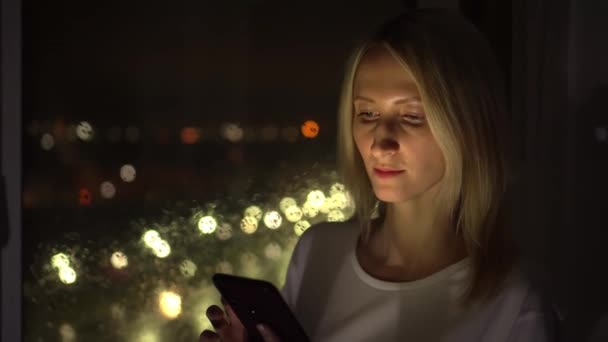 Женщина пользуется смартфоном. Свет от телефона освещает лицо. — стоковое видео