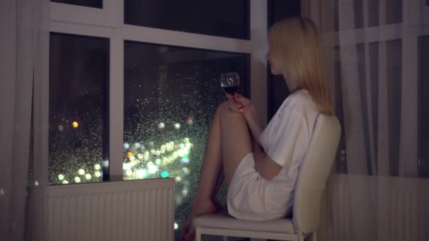 밤에 도시를 배경으로 한 여자가 와인 한 잔을 들고 있다. — 비디오