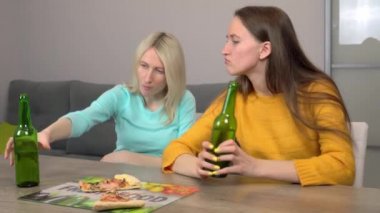 Mutfaktaki en mutlu iki kız arkadaş pizza yiyor ve bira içiyor..