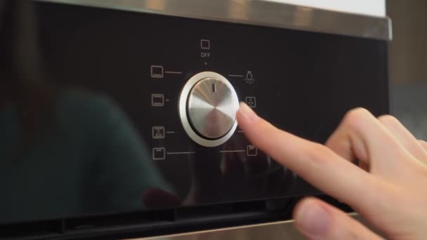 La mano de una mujer ajustando el horno eléctrico en la cocina, — Vídeos de Stock